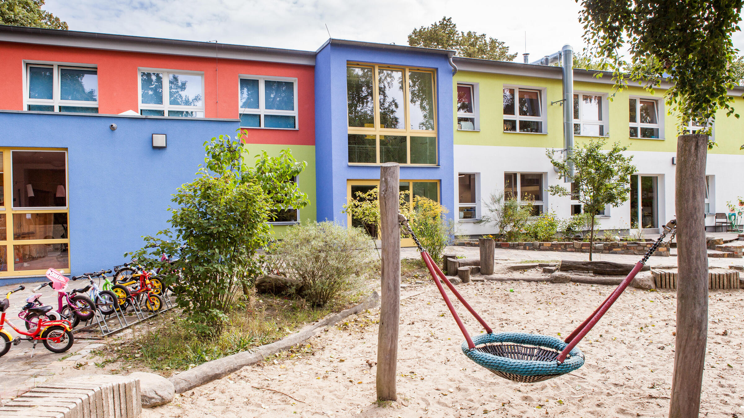 Foto Außenansicht Kita Engelhardstraße mit Sandkasten und Schaukel