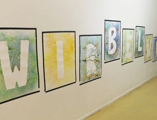 Humanistische Kita Friedrich-Engels-Straße in Berlin-Pankow: Tag der offenen Tür am 17. Mai 2025 An einer Wand hängen Bilder. Auf jedem Bild ist ein Großbuchstabe zu sehen. Zusammen ergeben sie das Wort „Wirbelwind“.