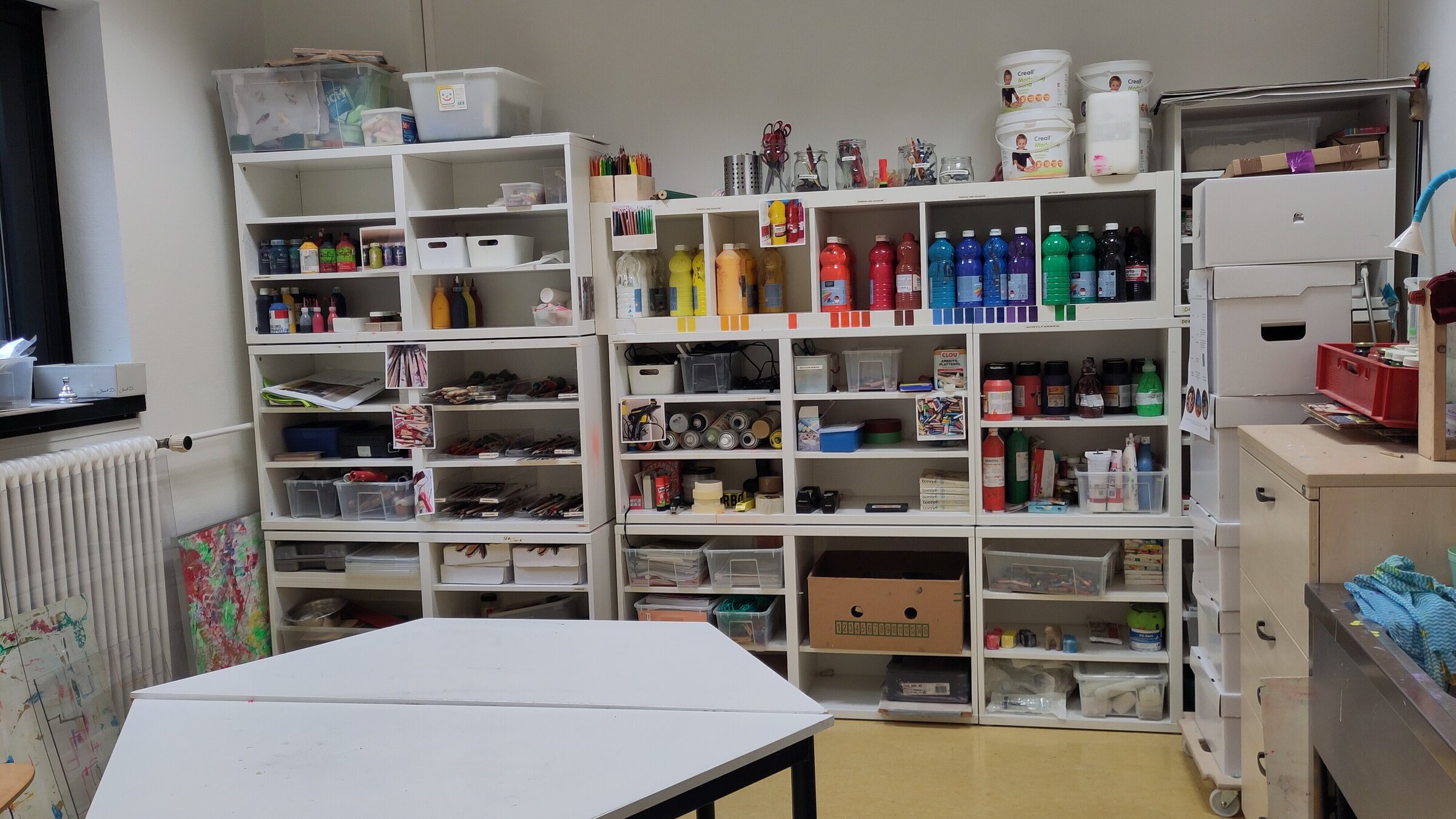 Eckiger Tisch vor Regalen im Atelier