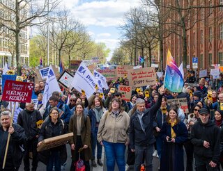 Psychosoziale Kontakt- und Beratungsstelle Brückentreff in Berlin: Rückblick Demo gegen Gemeindepsychiatrie-Kürzungen am 8. April 2025_ Demonstrierende laufen mit Fahnen und Plakaten auf einer Straße.