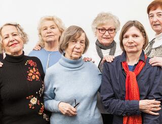 Berlner Seniorentelefon Team Zu sehen sind sechs ältere Frauen, die in zwei Reihen nebeneinander stehen. Sie schauen in die Kamera und lächeln.