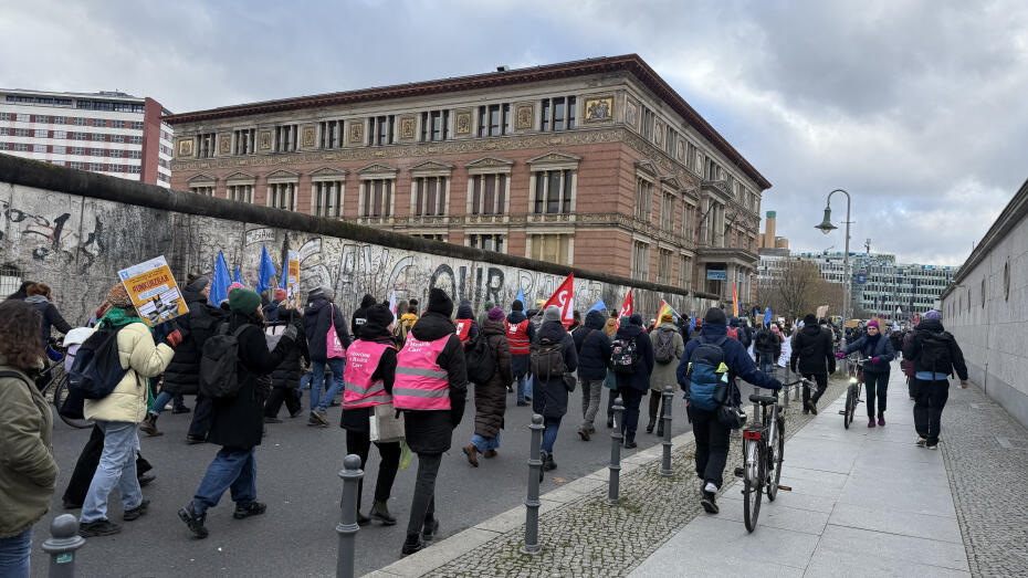 Auf einer Straße laufen Demonstrierende mit Fahnen und Plakaten.