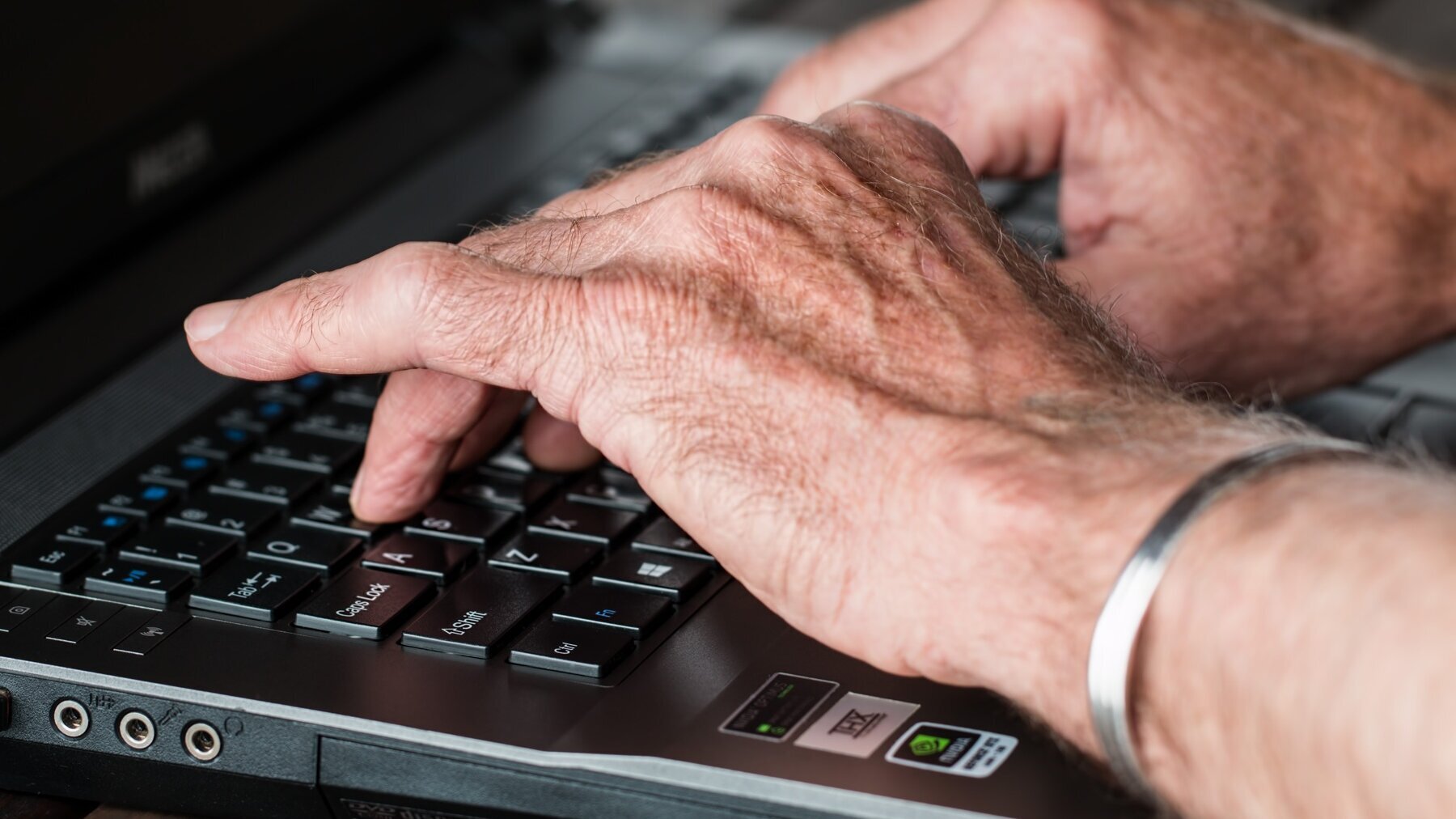 Hände tippen auf der Tastatur eines Laptops.