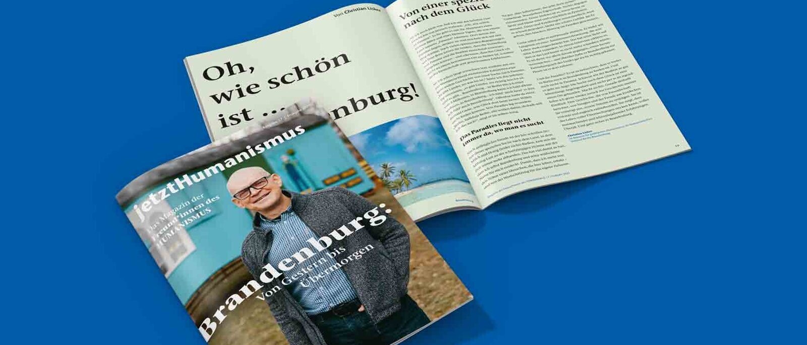 Ein Magazin liegt einmal geschlossen und einmal aufgeschlagen auf blauem Hintergrund.