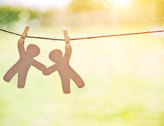 Kontakt- und Informationsstelle für Selbsthilfe in Berlin-Pankow: Selbsthilfegruppen für Betroffene Zwei Holzfiguren hängen an einer Schnur in der Luft. Jeweils eine Hand ist mit einer Wäscheklammer an der Schnur befestigt. Mit der anderen Hand halten sich die Figuren gegenseitig fest.