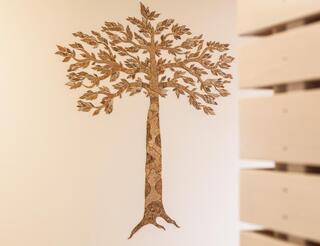 Kinderhospiz Berliner Herz: Kindertrauergruppen An einer Wand befindet sich eine Baumapplikation aus Kork. Rechts ist die Ecke einer Bretterwand zu sehen.