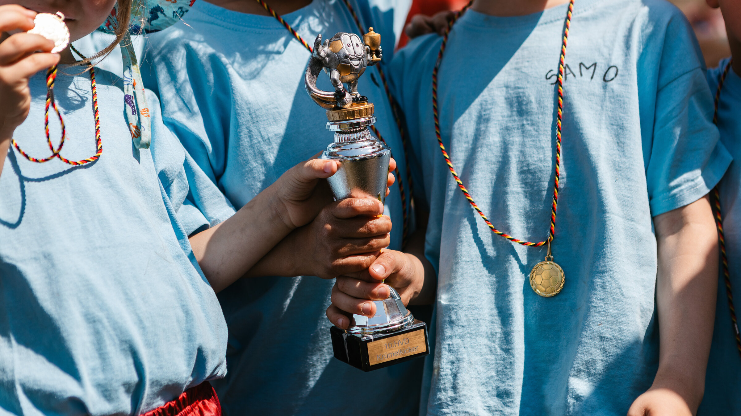 Kinderhände halten einen Pokal in der Hand.