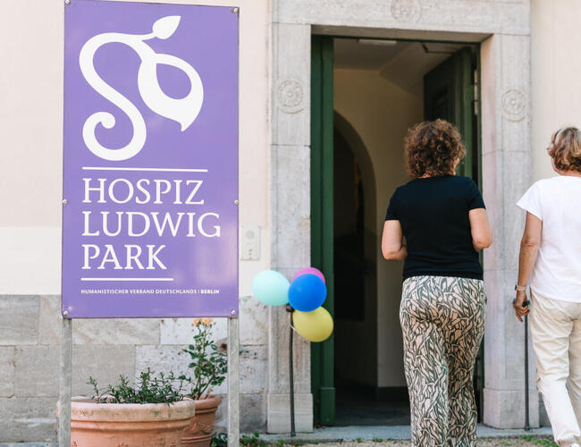 Zwei Personen laufen auf die Eingangstür des Hospizes LudwigPark in Berlin-Buch zu.
