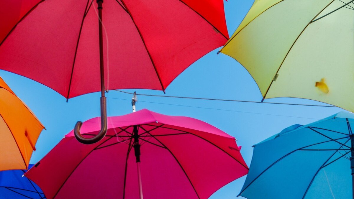 Bunte Regenschirme schweben im blauen Himmel.