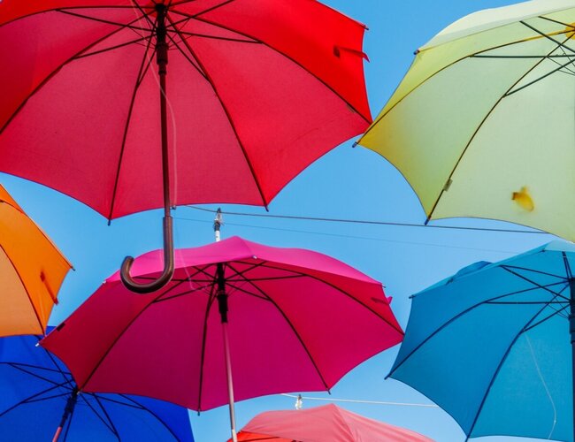 Bunte Regenschirme schweben im blauen Himmel.