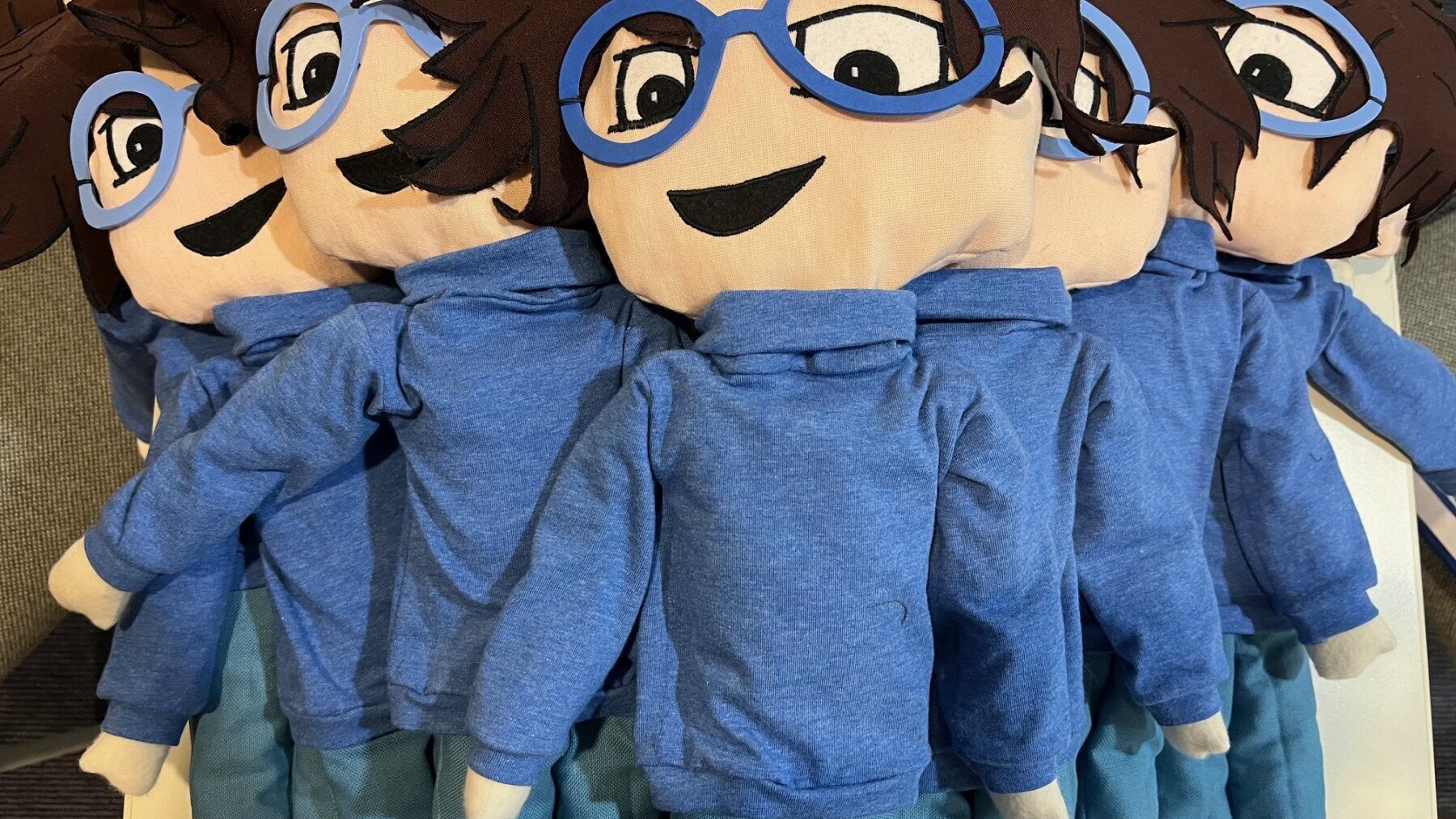 Pyramidenförmig liegen Stoffpuppen auf einem Stapel. Davon sind fünf zu sehen.