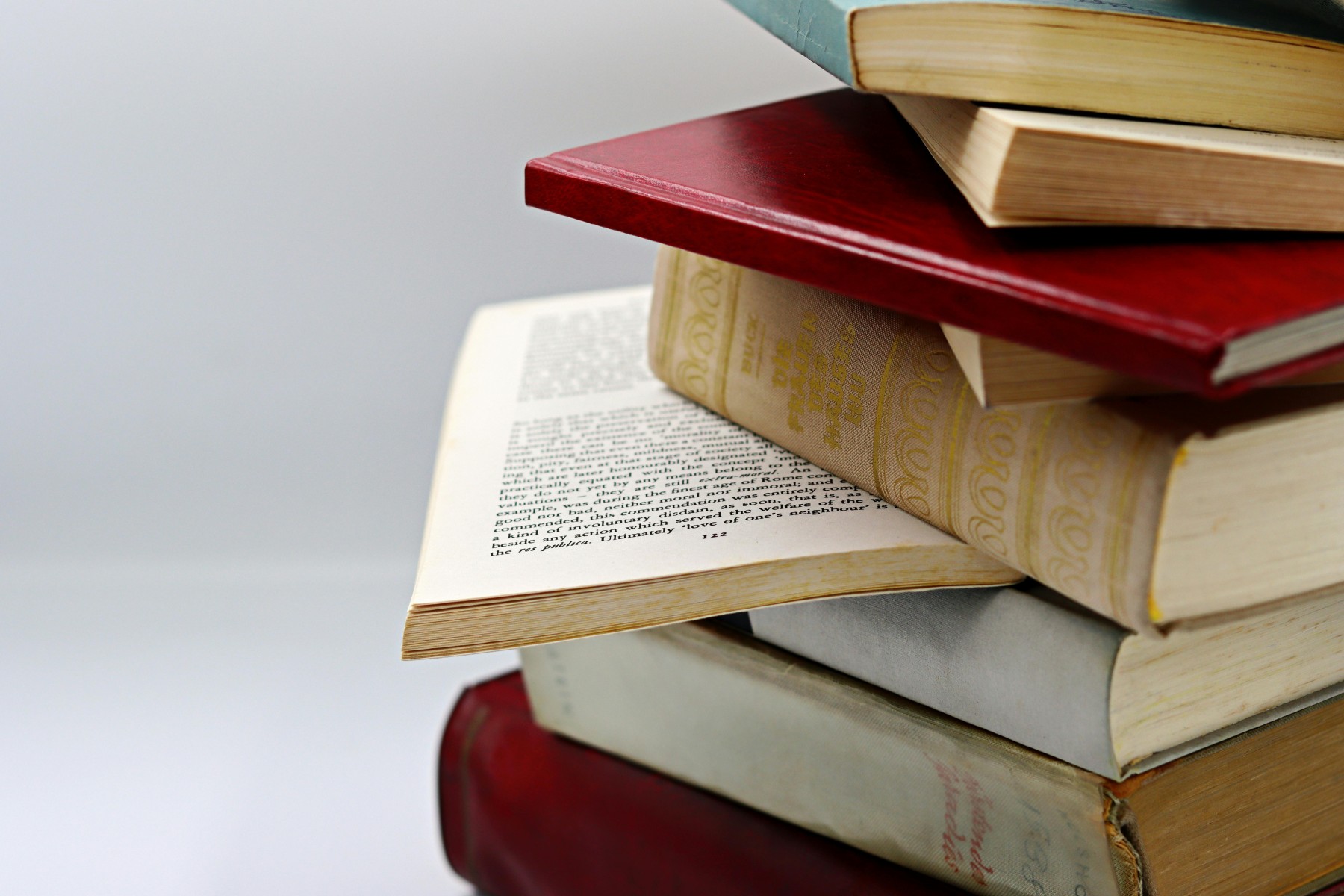 Rechts ist ein Stapel Bücher zu sehen, die nicht ordentlich Kante auf Kante übereinanderliegen.