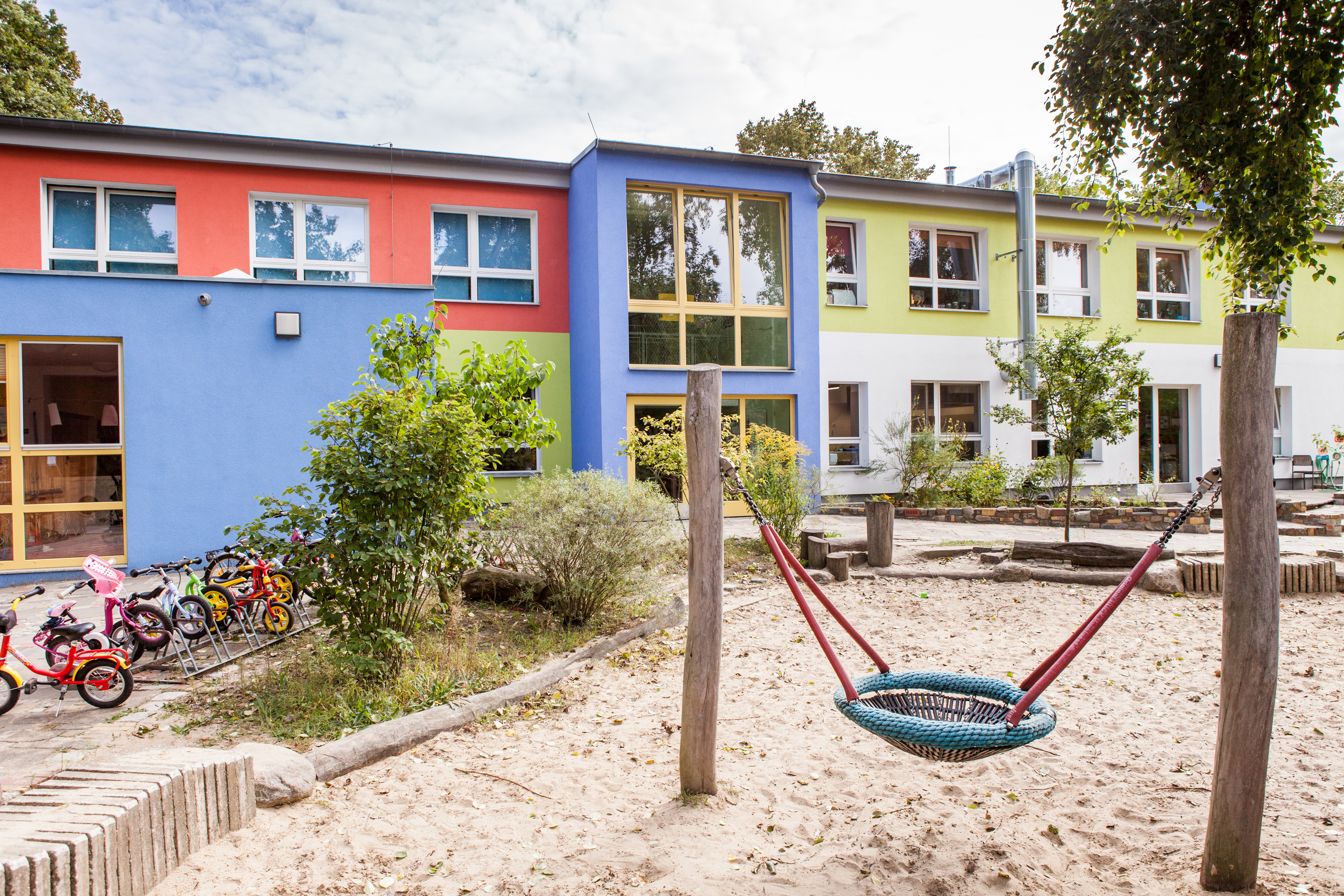 Foto Außenansicht Kita Engelhardstraße mit Sandkasten und Schaukel