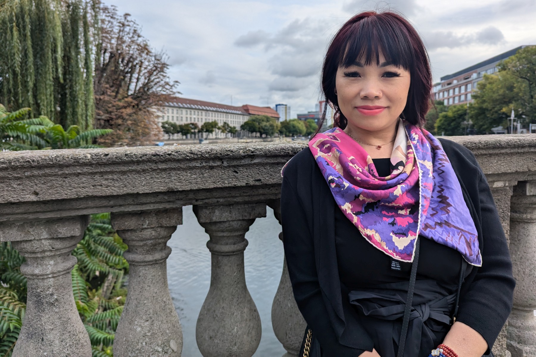 Thi My Hanh Vu, Koordinatorin des interkulturellen Hospizdienstes Dong Ban Ja, steht vor einem Brückengeländer.
