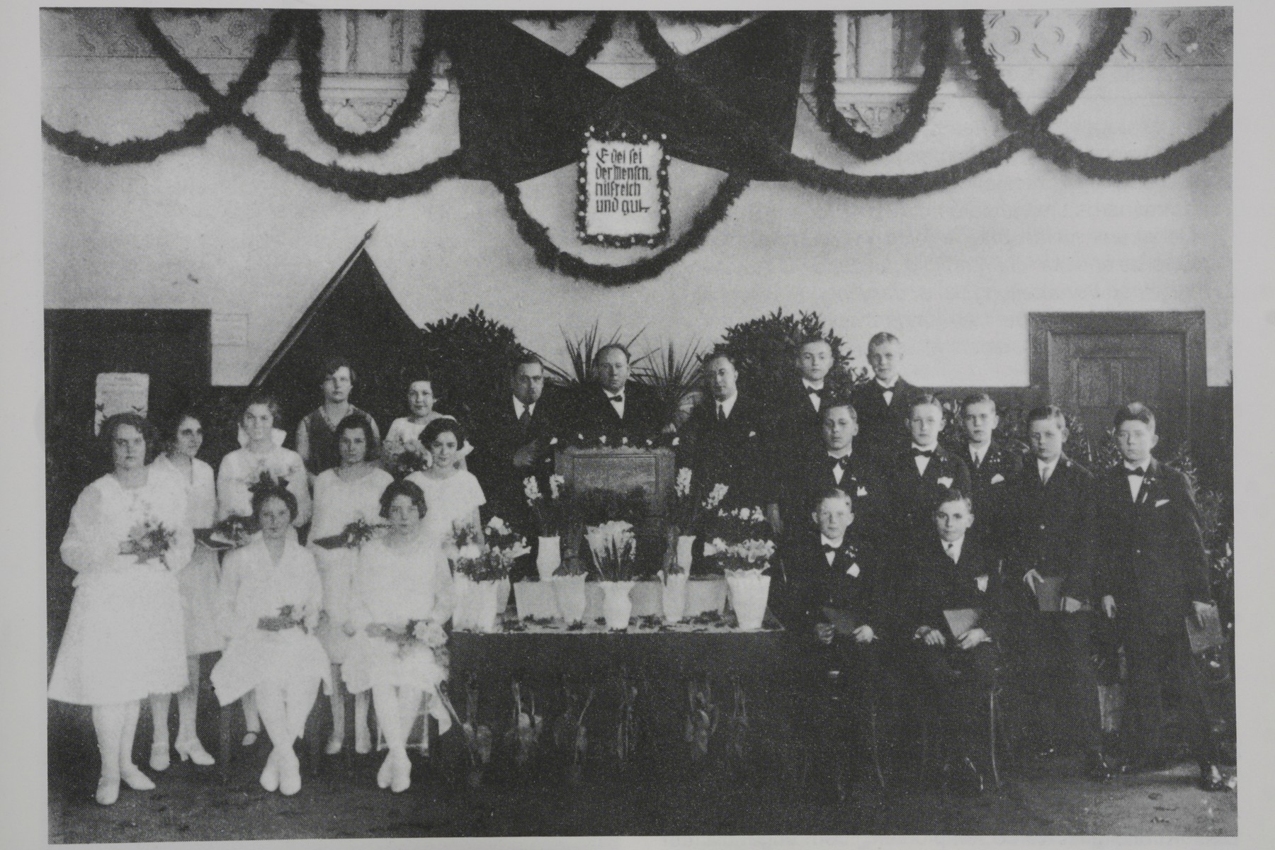 Dieses Schwarz-Weiß-Gruppenfoto zeigt eine Jugendweihe im Jahr 1928 in Berlin-Bohnsdorf: Links in weißen Kleidern sind Mädchen und rechts in schwarzen Anzügen Jungen zu sehen.