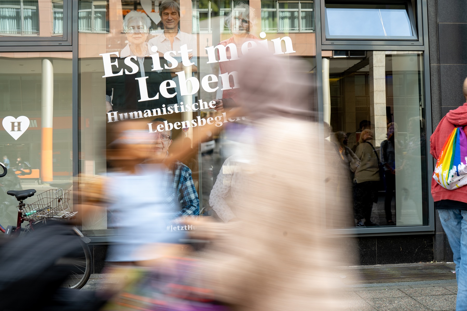 Menschen spiegeln sich in einem Schaufenster auf dem steht: "Es ist mein Leben".
