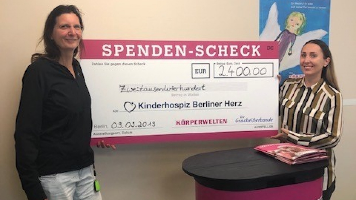 Beate Kachel von den KÖRPERWELTEN (r) übergibt den Spendenscheck an Kathi Bertolini, Pflegedienstleiterin des Kinderhospizes (l)